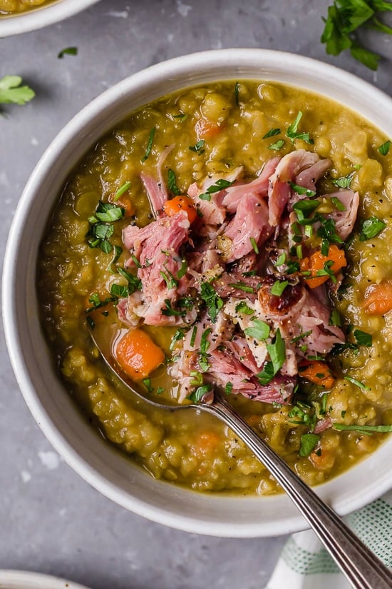 This easy split pea soup with ham is what I crave on cold nights! It's a comforting recipe made with just 6 ingredients not counting salt. A white bowl filled with split pea soup with ham.