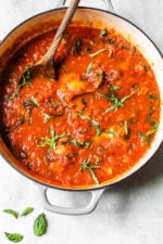 Overhead view of classic chicken cacciatore with peppers and tomatoes in a Dutch oven.