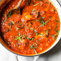 Overhead view of classic chicken cacciatore with peppers and tomatoes in a Dutch oven.
