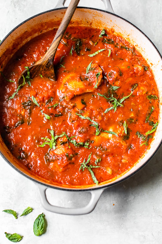 Overhead view of classic chicken cacciatore with peppers and tomatoes in a Dutch oven.