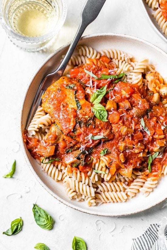 Chicken cacciatore is a rustic Italian chicken dish made with bell peppers and mushrooms slow-simmered in a rich tomato sauce with herbs. Overhead view of rustic chicken cacciatore served over pasta.