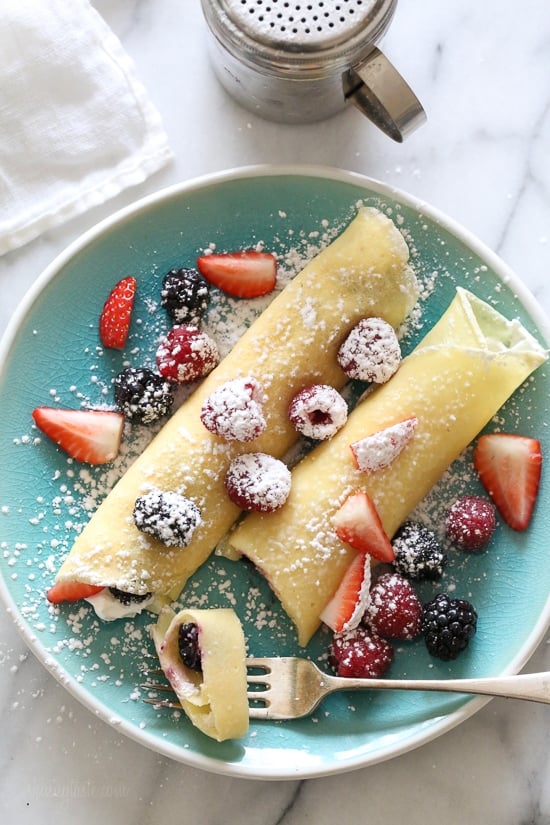 With just 4 main ingredients and everything prepared in the blend, this Easy Crepes Recipe is virtually foolproof! Blender crepes on a plate with fresh berries
