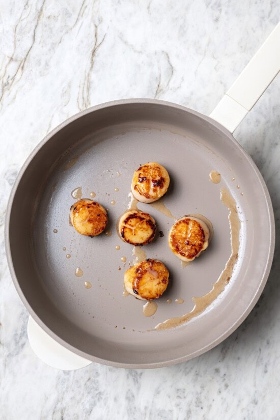 Pan seared scallops taste like a special occasion dinner but they’re easy enough for a weeknight. Serve over salad for a light, healthy meal! Overhead view of scallops searing in pan