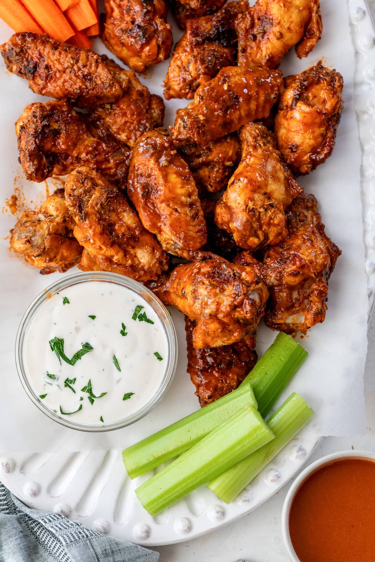 These homemade buffalo wings will be the hit at your next football party! They're baked in the oven and so much lighter than deep-fried. Overhead view of buffalo wings on a platter next to a bowl of blue cheese dressing and celery sticks.