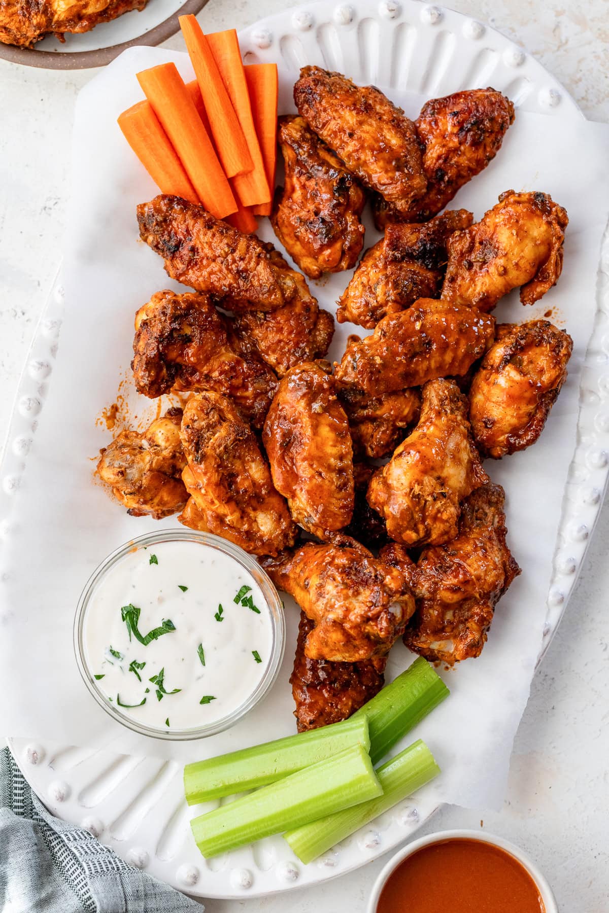 These homemade buffalo wings will be the hit at your next football party! They're baked in the oven and so much lighter than deep-fried. Overhead view of buffalo wings on a platter next to a bowl of blue cheese dressing and celery sticks.