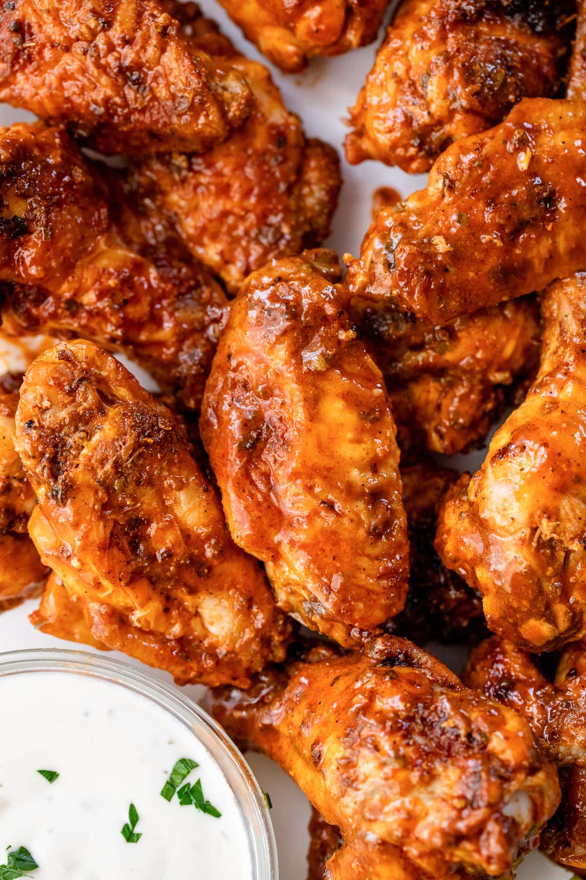 These homemade buffalo wings will be the hit at your next football party! They're baked in the oven and so much lighter than deep-fried. Close up of baked buffalo wings next to a bowl of blue cheese dressing.