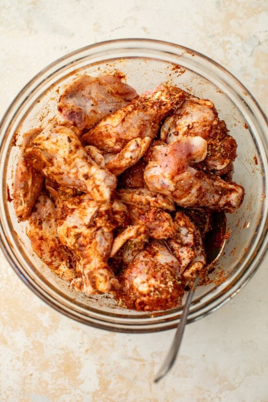These homemade buffalo wings will be the hit at your next football party! They're baked in the oven and so much lighter than deep-fried. Chicken wings tossed in buffalo marinade in a bowl.