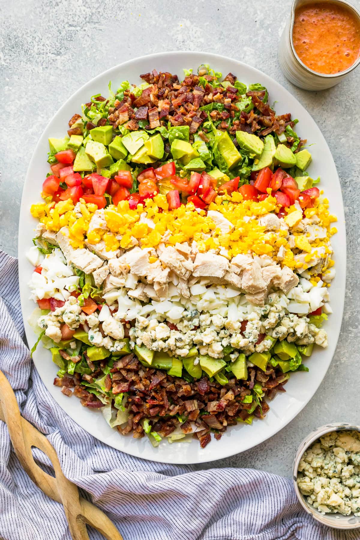Layers of hard boiled eggs, bacon, blue cheese, tomatoes and avocado make up this classic Cobb salad recipe. It's the perfect lunch salad! Overhead view of Cobb salad with red wine tomato vinaigrette