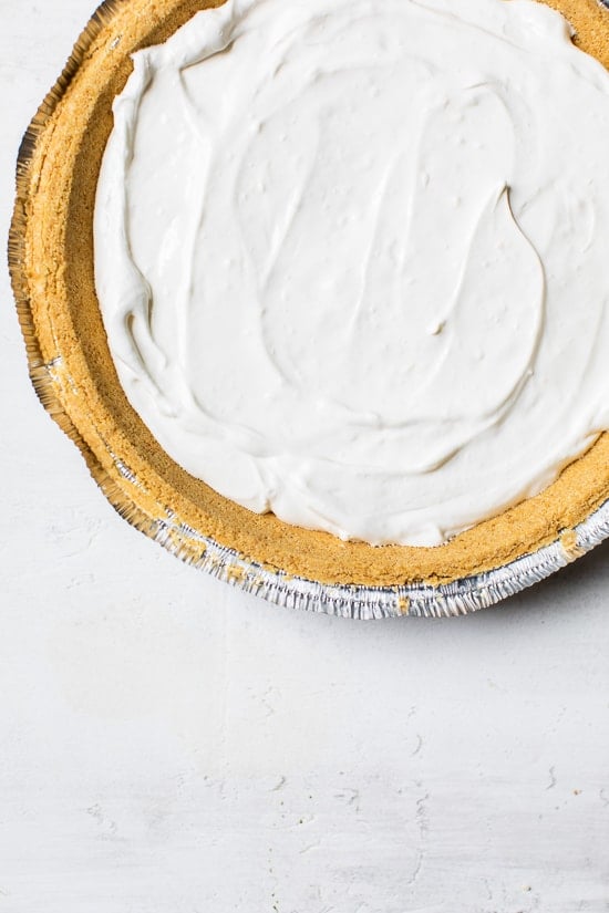 This easy no-bake cheesecake is light, dreamy and so easy to make, you don’t even need an oven. A little slice of heaven! Overhead view of no-bake cheesecake filling added to crust