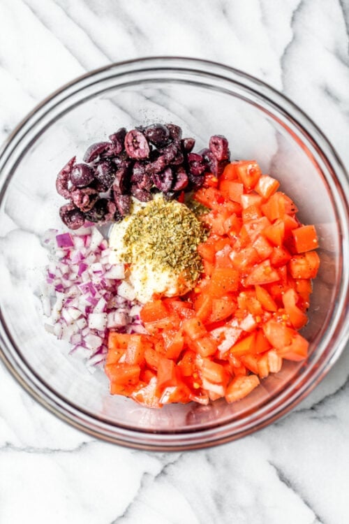 tomatoes, black plives and red onion in a bowl