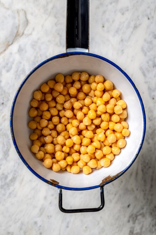 Smoky bell peppers add so much flavor to this roasted red pepper hummus recipe! Pair it with your favorite veggies for a healthy snack. Overhead view of drained chickpeas