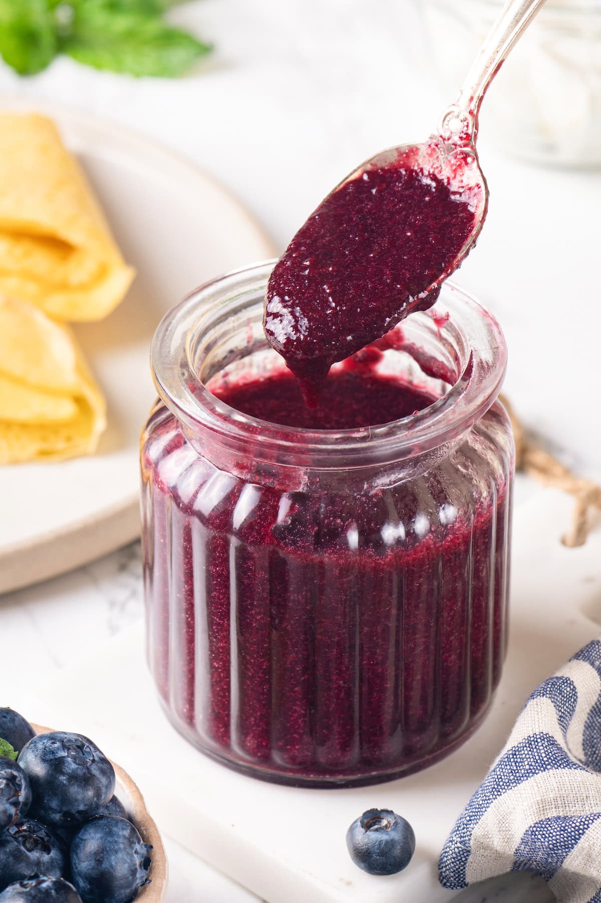 This easy blueberry compote recipe is a 3-ingredient fruit topping perfect for serving over ice cream, yogurt, and more. So summery! Jar of blueberry compote with spoon