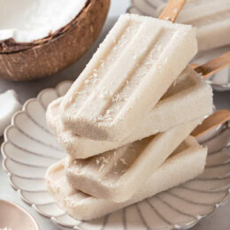 Four coconut popsicles stacked on plate