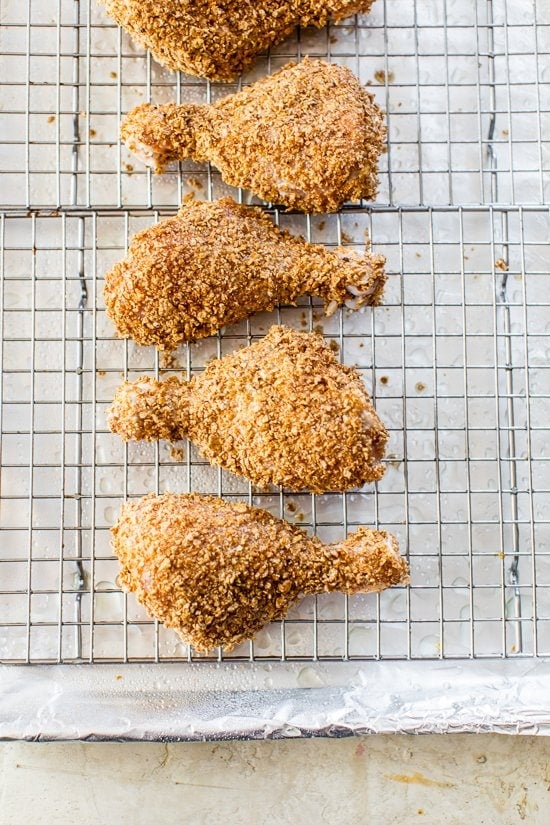 This healthy oven fried chicken is moist on the inside, golden and extra crispy on the outside thanks to a secret ingredient: bran flakes! Chicken drumsticks on a wire rack before baking.