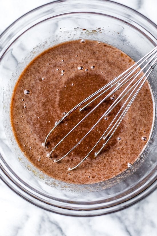 This Chocolate Zucchini Bread is so rich and delicious, no one will guess that it's secretly healthy! Add walnuts for crunch in every bite. Overhead view of wet ingredients for chocolate zucchini bread in bowl with whisk