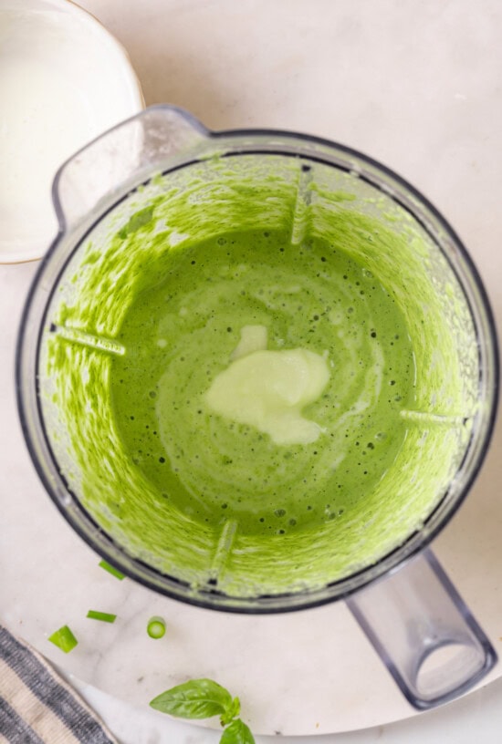 Basil green goddess dressing is the perfect way to give your next salad an upgrade! This version is lightened up, but still rich and creamy. Overhead view of sour cream added to blender of basil green goddess dressing