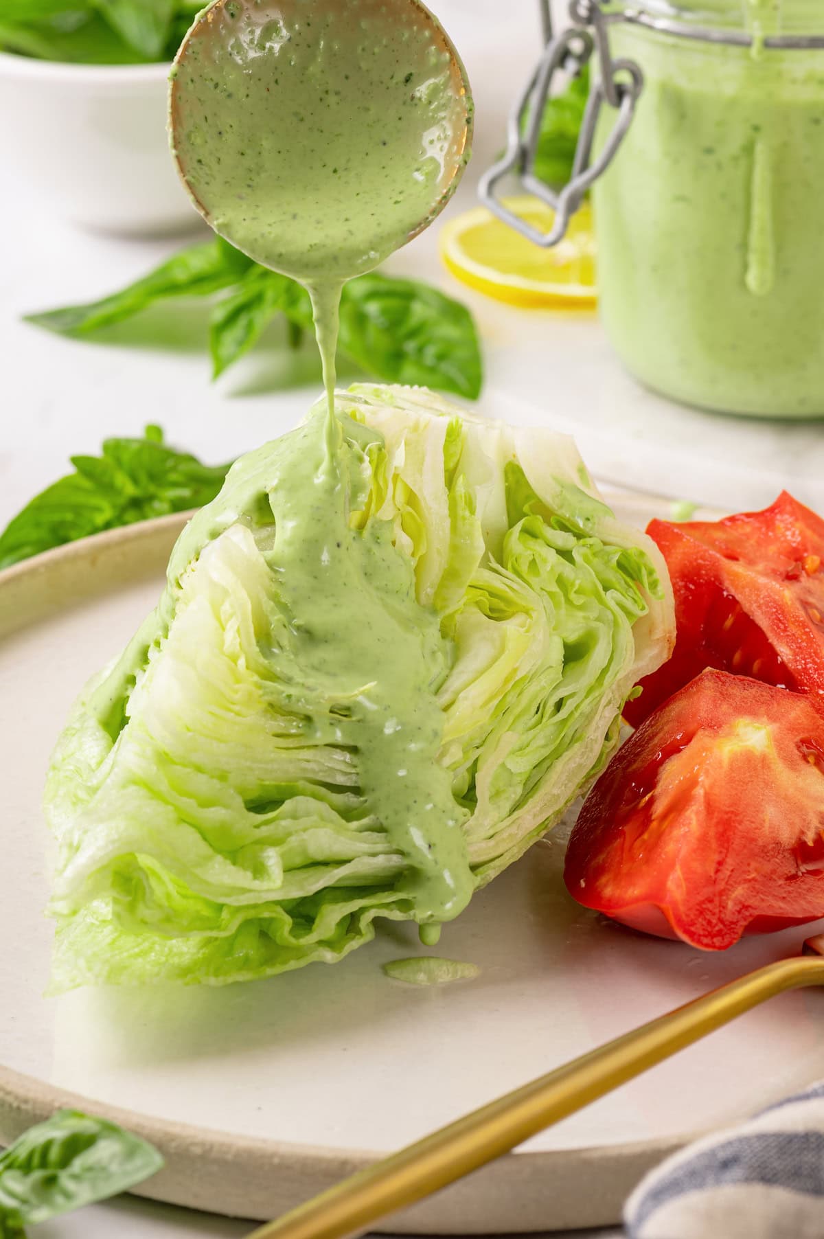 Basil green goddess dressing is the perfect way to give your next salad an upgrade! This version is lightened up, but still rich and creamy. Drizzling basil green goddess dressing over wedge salad