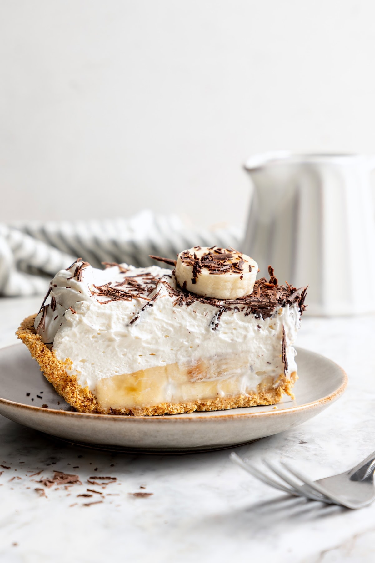 This easy banana cream pie recipe is creamy, fluffy, and full of fresh banana flavor. It’s a lighter take on a classic dessert! Slice of no bake banana cream pie on plate.