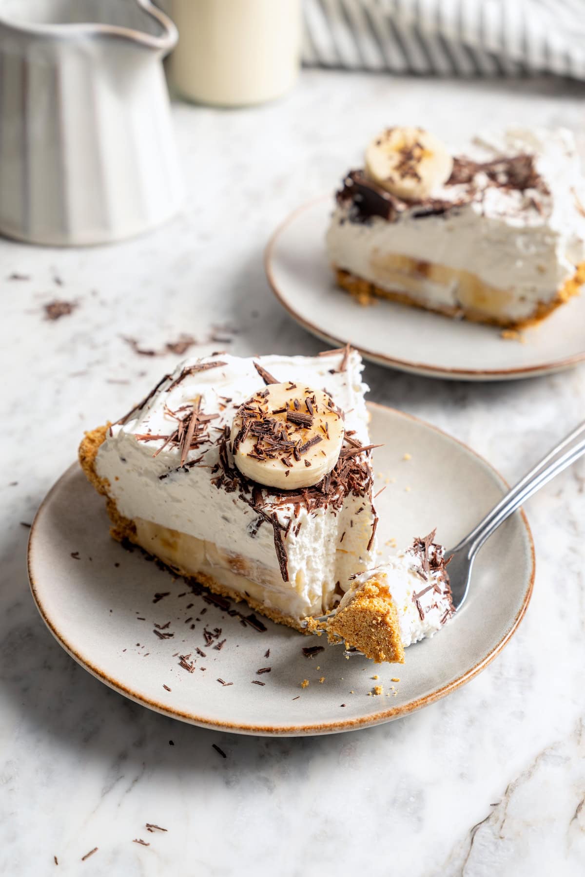 This easy banana cream pie recipe is creamy, fluffy, and full of fresh banana flavor. It’s a lighter take on a classic dessert! Slice of banana cream pie on plate with tip of pie on fork.