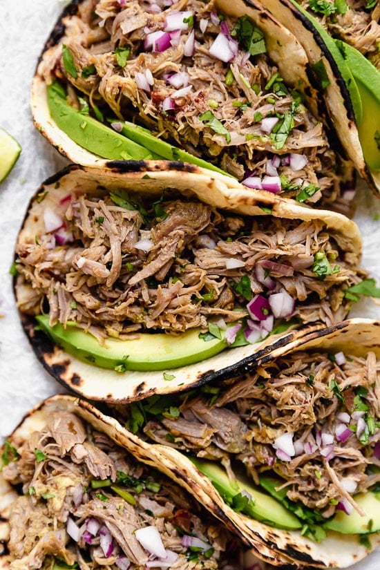 Slow cooked until tender then crisped in the oven, these pork carnitas are practically effortless to make and perfect for meal prep. Slow cooker carnitas tacos with avocado slices.