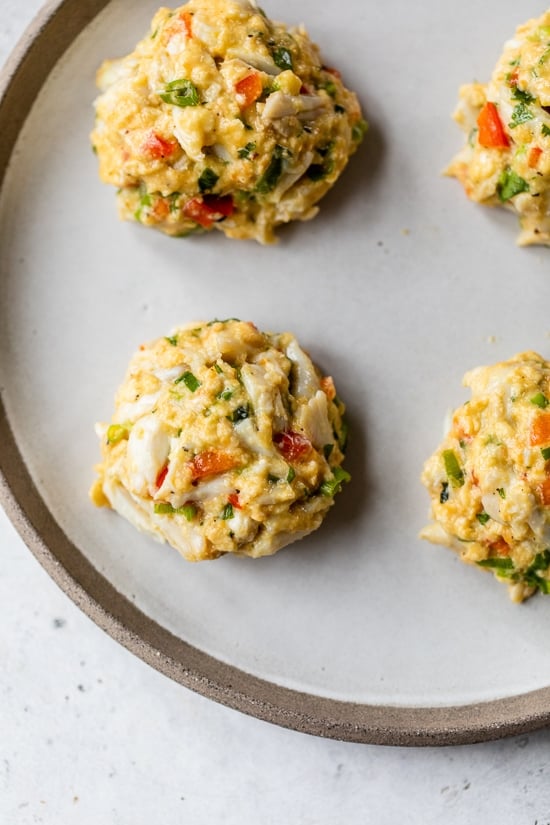 This easy baked crab cakes recipe combines juicy lump crab meat, simple seasonings, and fresh herbs. Perfect as an appetizer or light dinner! Chilled crab cake patties on a plate.