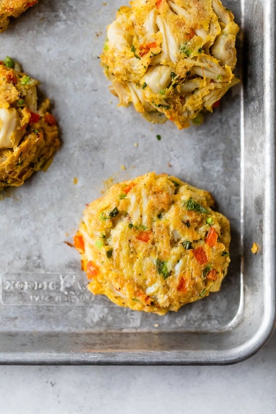 This easy baked crab cakes recipe combines juicy lump crab meat, simple seasonings, and fresh herbs. Perfect as an appetizer or light dinner! Baked crab cakes on a baking sheet.