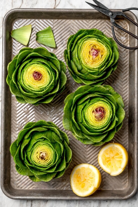 Stuffed artichokes are a classic Italian dish made with crispy, cheesy breadcrumbs. My version is a bit lighter but just as delicious! Overhead view of prepped artichokes on pan