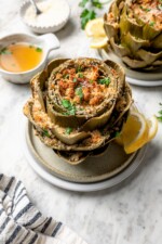 Stuffed artichoke on plate with lemon slices