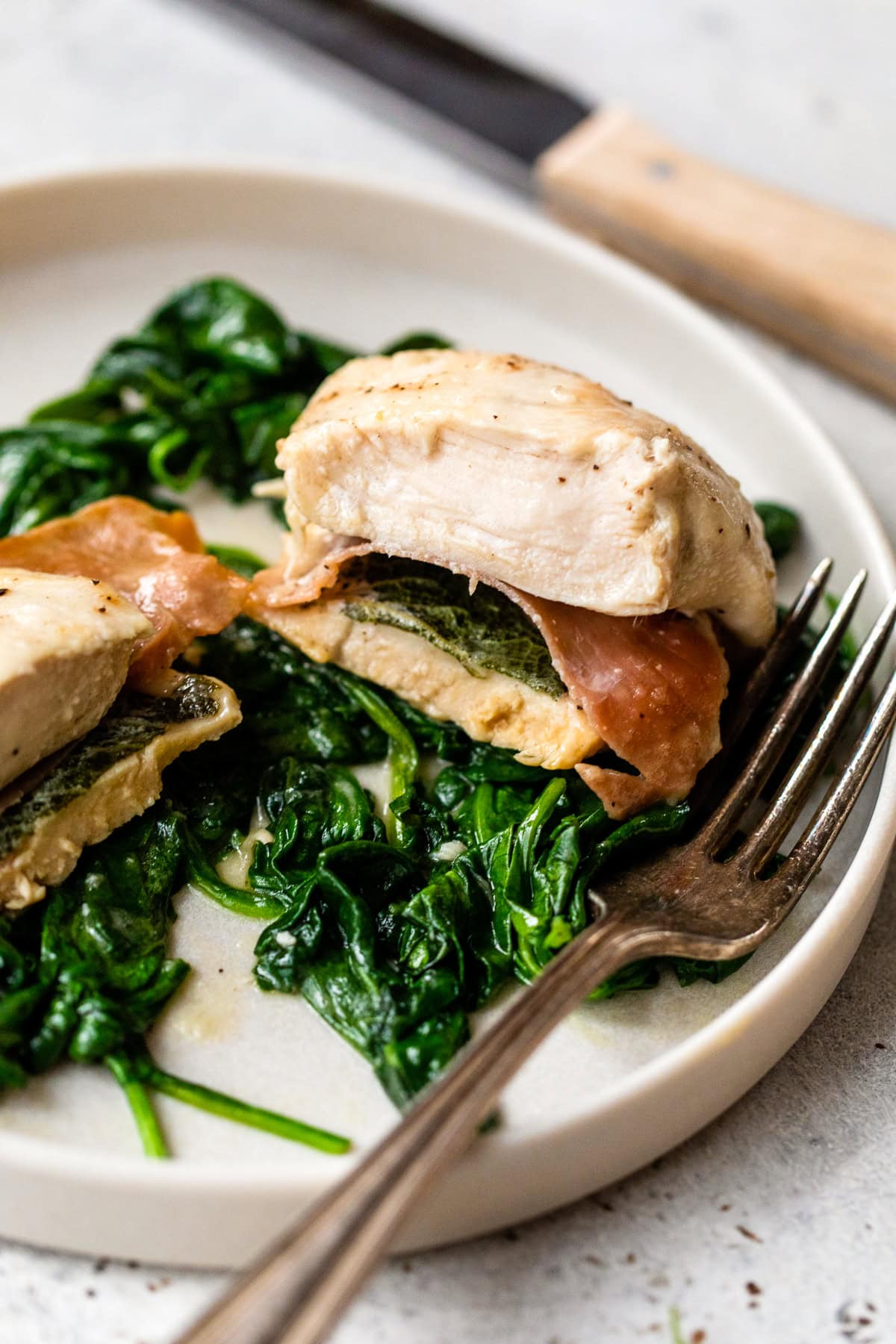 This lighter chicken saltimbocca is a restaurant-quality dinner with chicken cutlets stuffed with prosciutto and sage in white wine sauce. Chicken Saltimbocca with spinach on plate