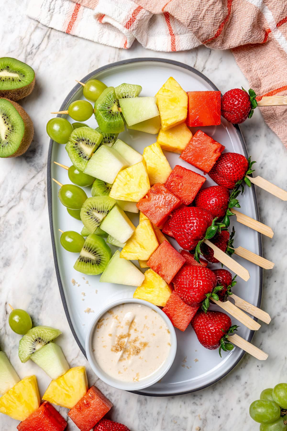 Fruit kabobs are the easiest summer dessert! Made with a rainbow of fruit threaded onto skewers, they’re perfect with a creamy fruit dip. Rainbow fruit kabobs on platter with dip