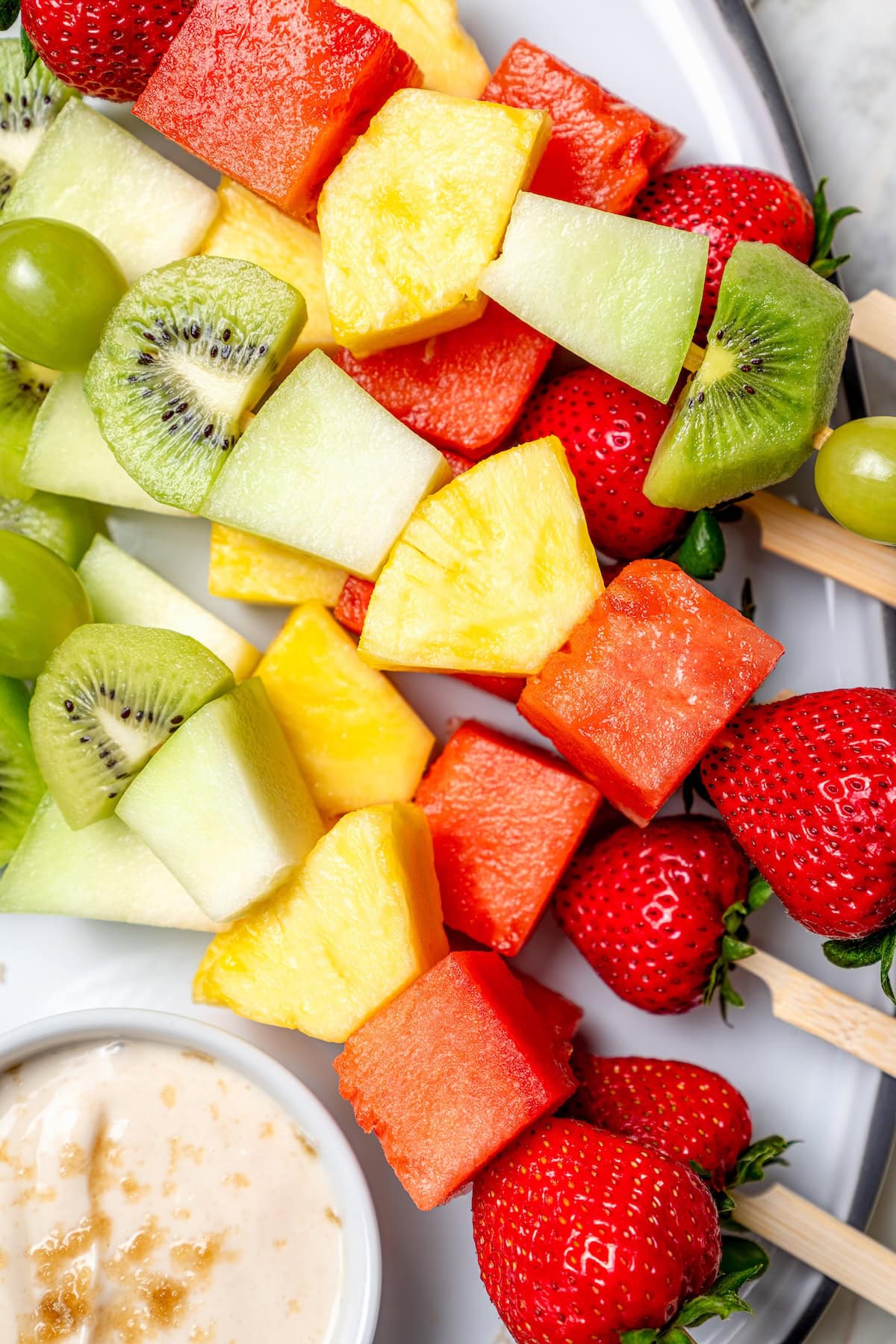 Fruit kabobs are the easiest summer dessert! Made with a rainbow of fruit threaded onto skewers, they’re perfect with a creamy fruit dip. Rainbow fruit kabobs on platter