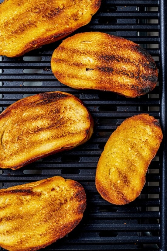 With juicy heirloom tomatoes, crisp cubes of bread, cucumber, and fresh basil, this panzanella recipe is a dish you’ll find yourself making all summer long. Serve it as a side or as a light meal. Overhead view of bread slices toasting on indoor grill