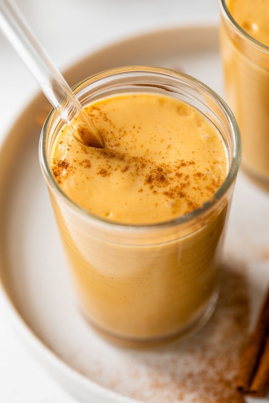 Made with Greek yogurt, pumpkin puree, and pumpkin pie spice, this Pumpkin Smoothie tastes just like a slice of pumpkin pie. A pumpkin pie smoothie in a glass with a straw