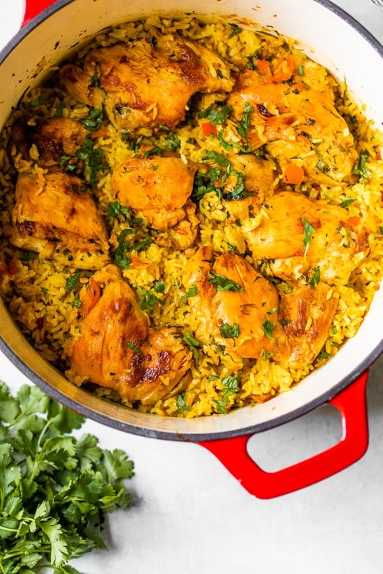 Authentic Arroz Con Pollo, or Latin chicken and rice, is the ultimate one-pot meal. It’s a classic Latin dish that I grew up with and love! Overhead view of Arroz Con Pollo in a red Dutch oven.