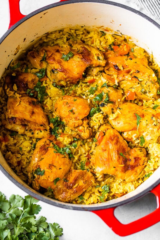 Authentic Arroz Con Pollo, or Latin chicken and rice, is the ultimate one-pot meal. It’s a classic Latin dish that I grew up with and love! Overhead view of Arroz Con Pollo in a red Dutch oven.