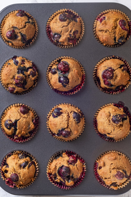 A classic blueberry muffin recipe lightened up with whole wheat flour and applesauce in place of the oil. So moist and delicious! Overhead view of blueberry muffin recipe baked in pan