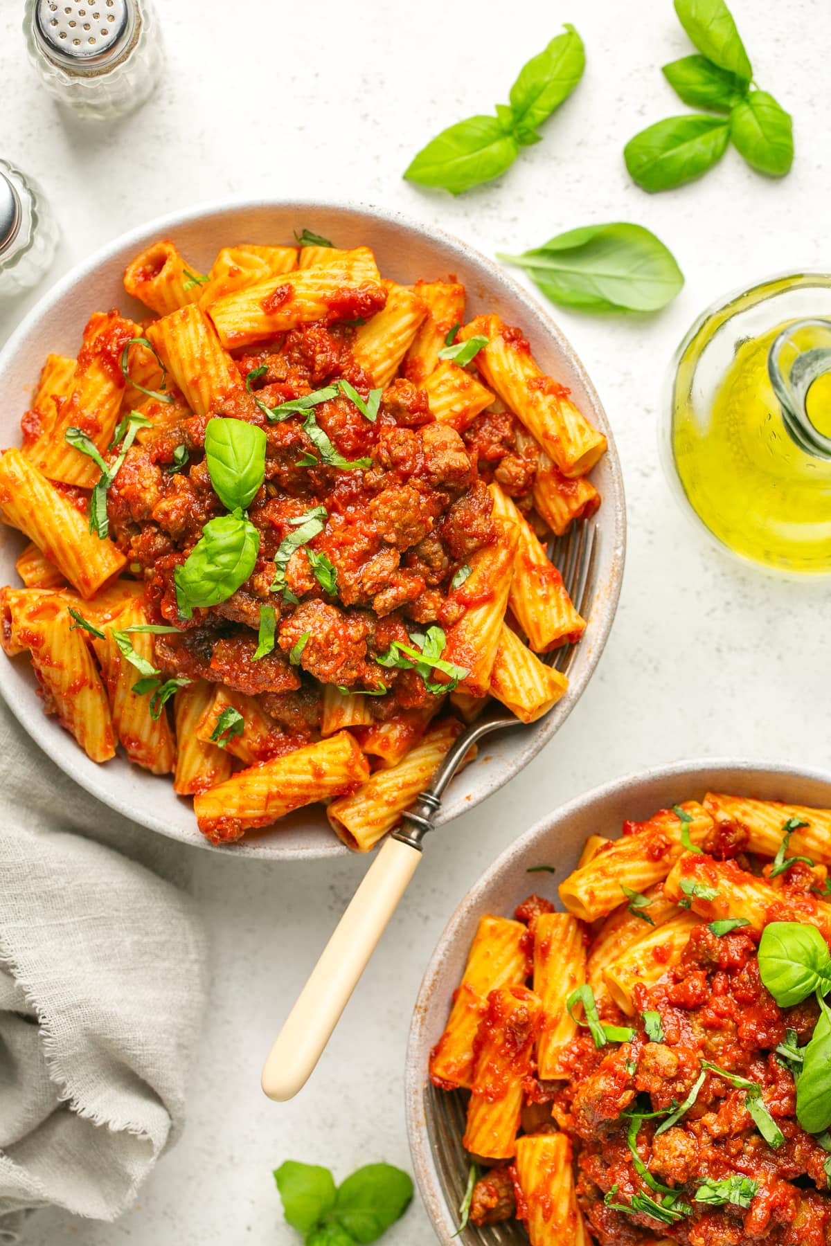 This easy, 5-ingredient sausage pasta sauce is made in the crock pot with flavorful chicken or turkey Italian sausage. Perfect for weeknights! Overhead view of two bowls with sausage pasta sauce served over rigatoni.