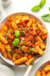 Overhead view of a bowl with sausage pasta sauce served over rigatoni.