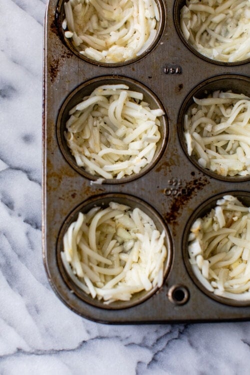 shredded potatoes in a muffin tin