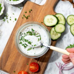 Bowl of buttermilk ranch dressing on board with spoon.