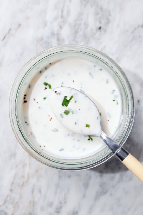 This lightened-up buttermilk ranch dressing is creamy, tangy, and full of fresh herbs. It’s an easy, lighter take on a classic favorite. Spoonful of buttermilk ranch dressing set in bowl.