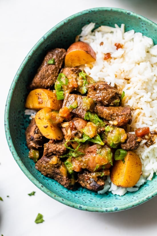Carne Guisada or Latin Beef Stew is made with chunks of beef simmered in beer with scallions, garlic, tomatoes, cumin and cilantro.