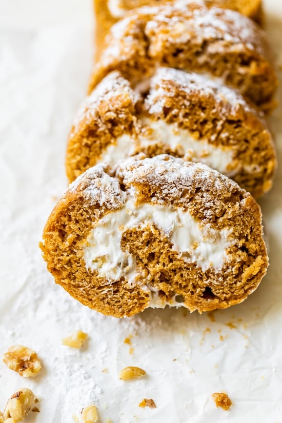 This classic pumpkin roll recipe features an irresistible pumpkin spice sponge cake with a tangy cream cheese filling. Perfect for holidays! Overhead view of a sliced pumpkin roll