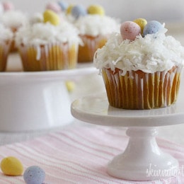A quick and easy coconut cupcake made with a box white cake mix, light coconut milk and apple sauce. No butter, no oil necessary for this lower calorie cupcake recipe! Sweetened coconut flakes are combined with a light cream cheese frosting for a divine finish!