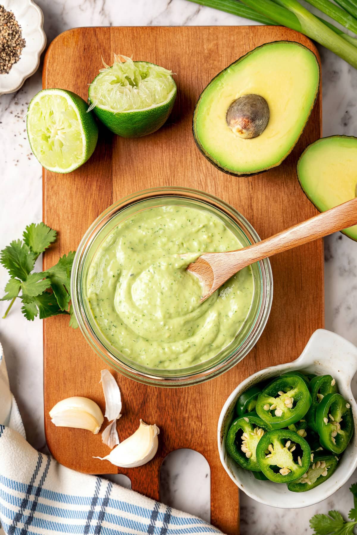 Creamy, bright, and tangy thanks to a buttermilk base, this avocado cilantro lime dressing is perfect for salads, tacos, and dipping veggies. Glass jar of avocado cilantro lime dressing with wooden spoon.