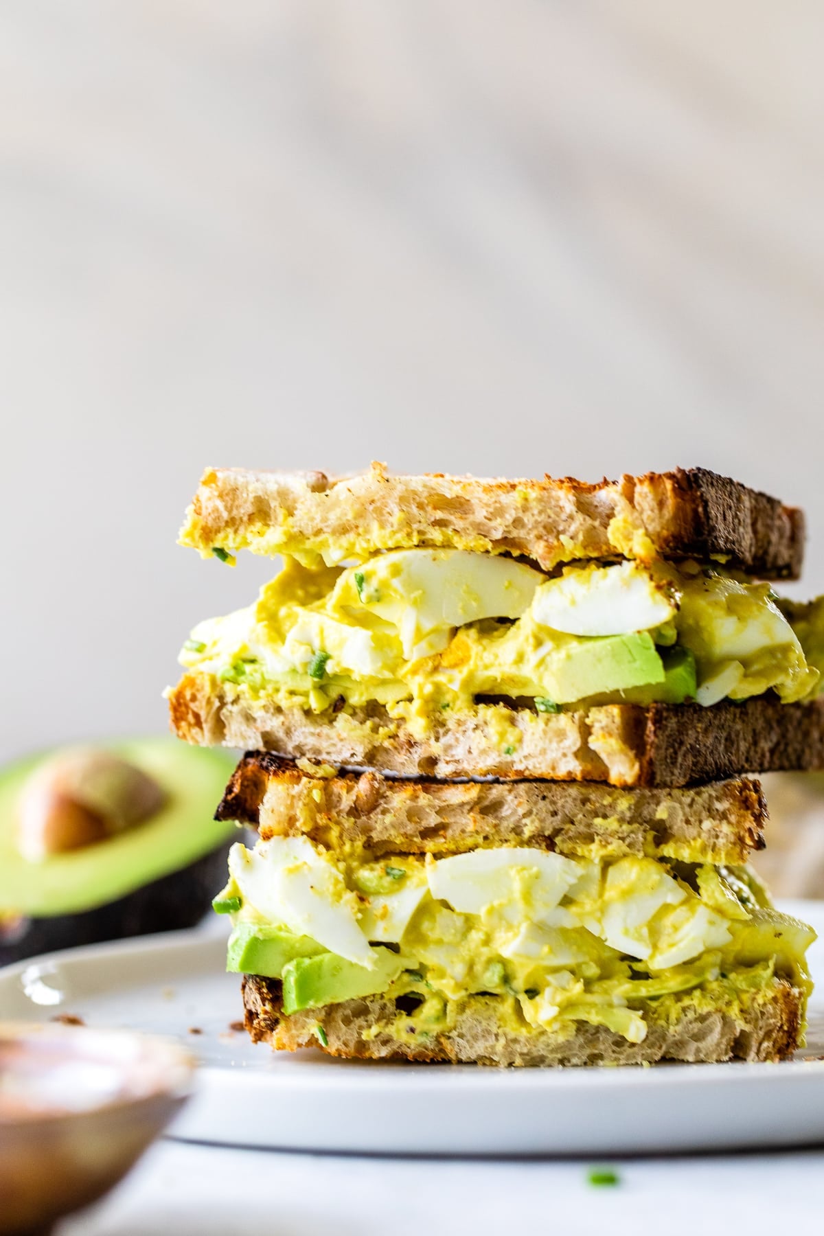 This avocado egg salad uses half the egg yolks and adds lots of healthy fats from avocado. An easy healthy, high protein lunch! Avocado Egg Salad sandwich cut in half.