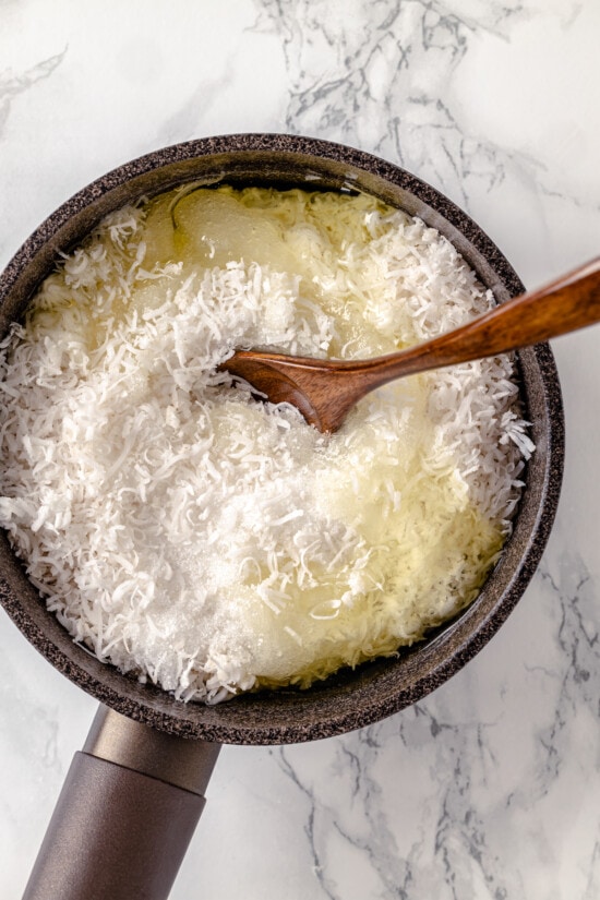 Made with sweetened coconut flakes, egg whites, and just a few other ingredients, Coconut Macaroons are moist, chewy, and perfectly flavored. A wooden spoon stirring shredded coconut and egg whites