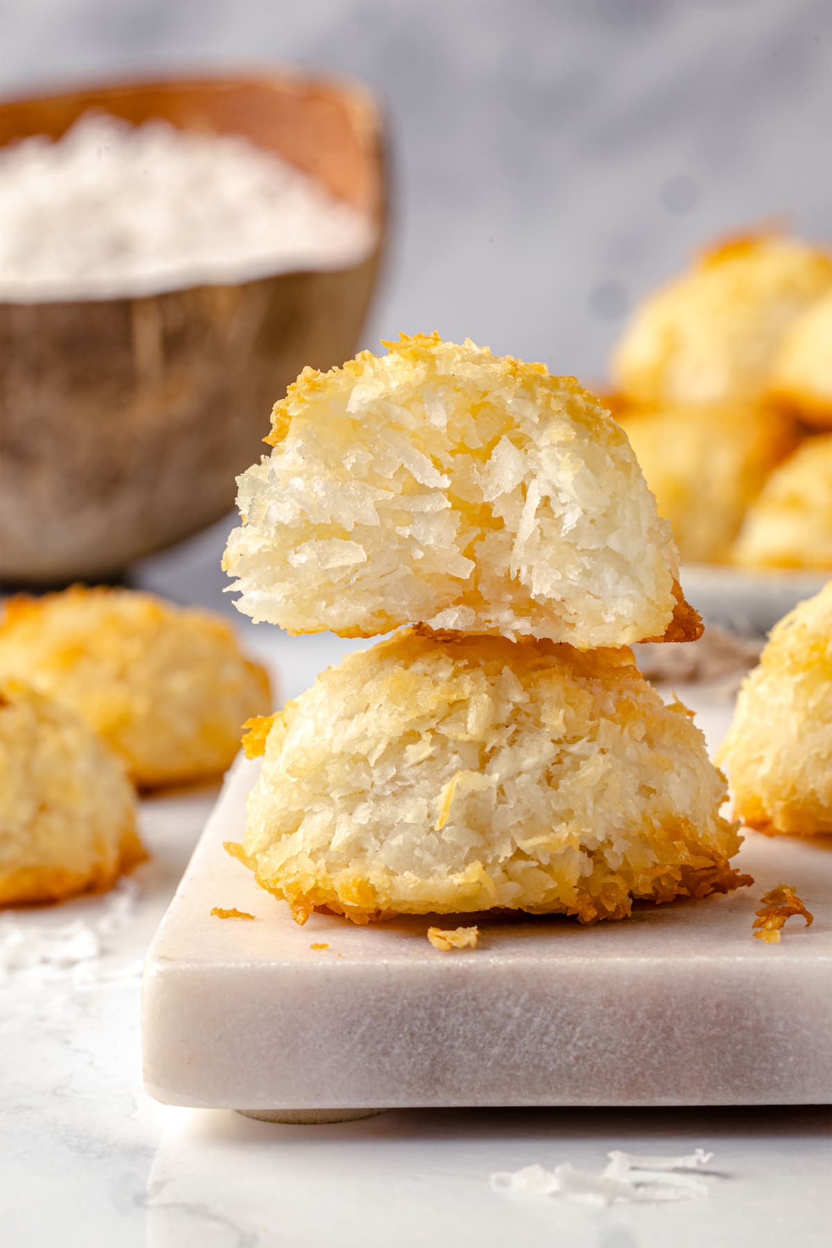 Made with sweetened coconut flakes, egg whites, and just a few other ingredients, Coconut Macaroons are moist, chewy, and perfectly flavored. Two coconut macaroons stacked on each other, one showing the inside.