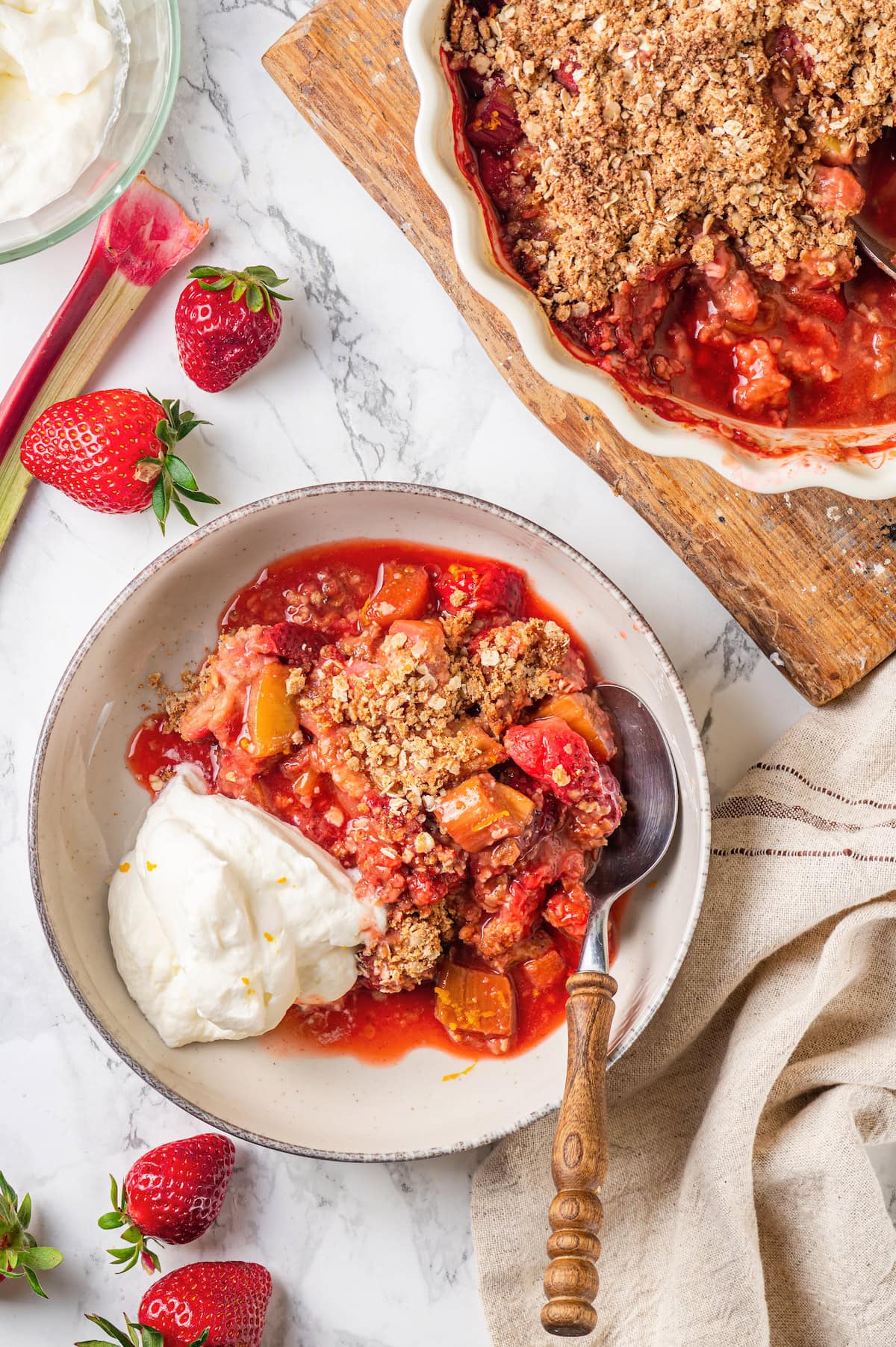 Honey adds the perfect amount of sweetness to the filling in this strawberry rhubarb crisp recipe. Easy to make and impossible to resist! Overhead view of strawberry rhubarb crisp in serving bowl and baking dish