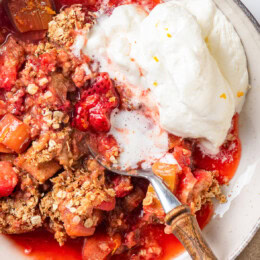 Overhead view of strawberry rhubarb crisp in bowl with whipped cream